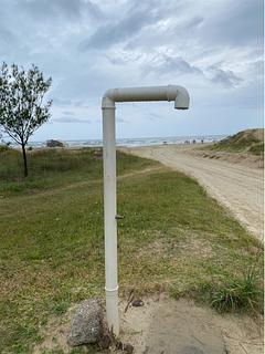 Chuveiro público perto da praia com estacionamento gratuito informal na frente